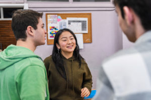 Teenagers chatting and smiling together in a lively high school classroom, enjoying moments of friendship and connection while learning
