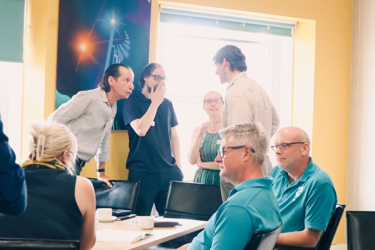 Participants networking and discussing ideas around a meeting table during a workshop event.